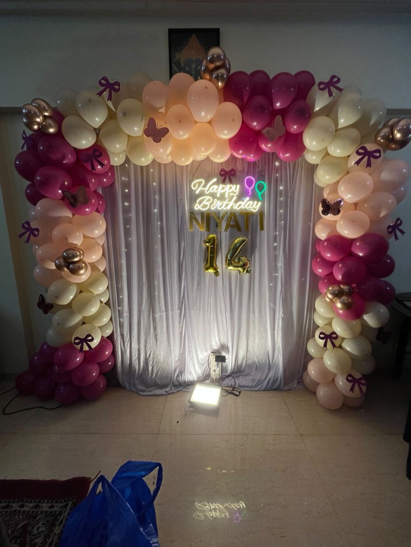 Wine, peach and ivory balloon frame with bows, butterflies, a neon Happy Birthday and gold number fourteen over a draped backdrop