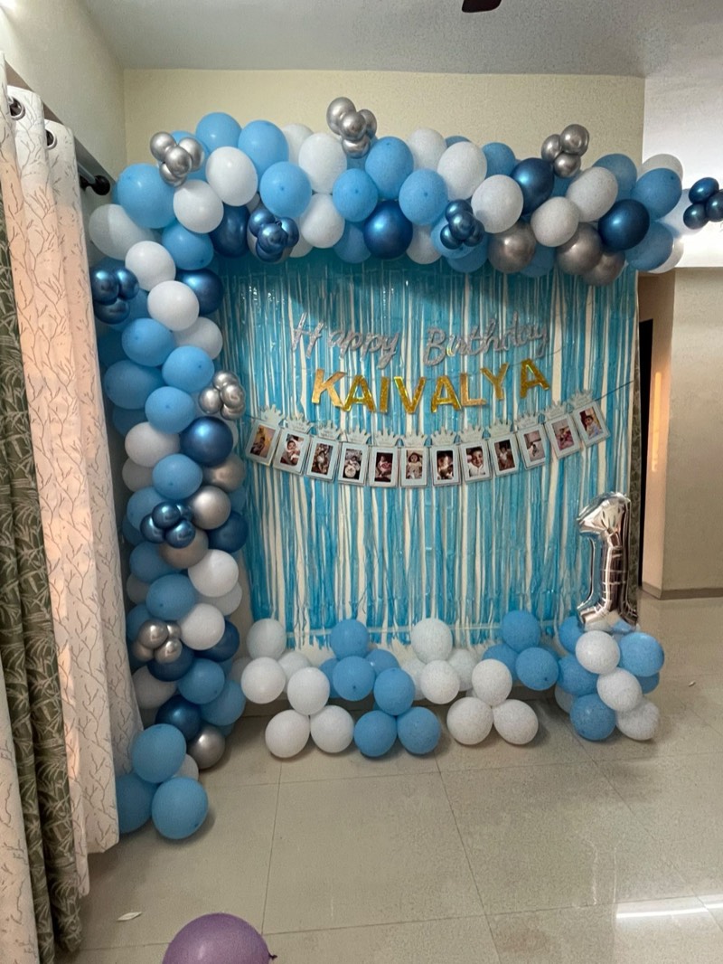 Blue, white and silver balloon garland with a blue foil curtain and a month-by-month photo banner