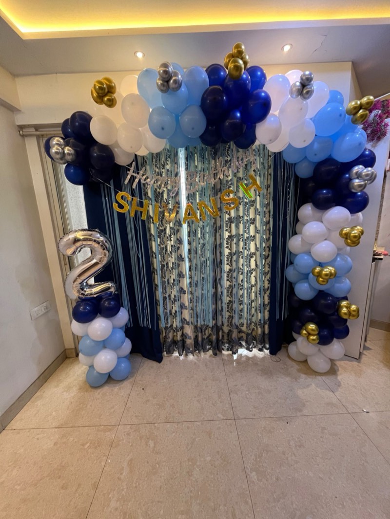 Blue, white and gold balloon garland framing a curtain backdrop in a home
