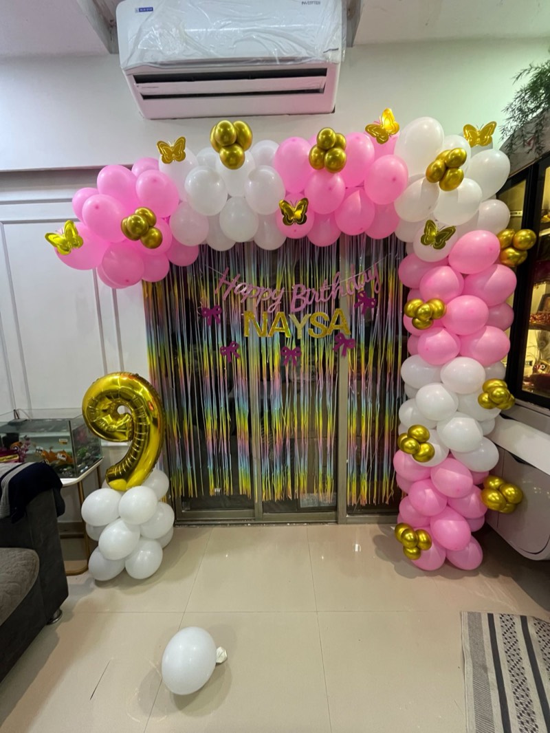 Pink, white and gold balloon garland with golden butterflies, a rainbow fringe curtain and a gold number nine
