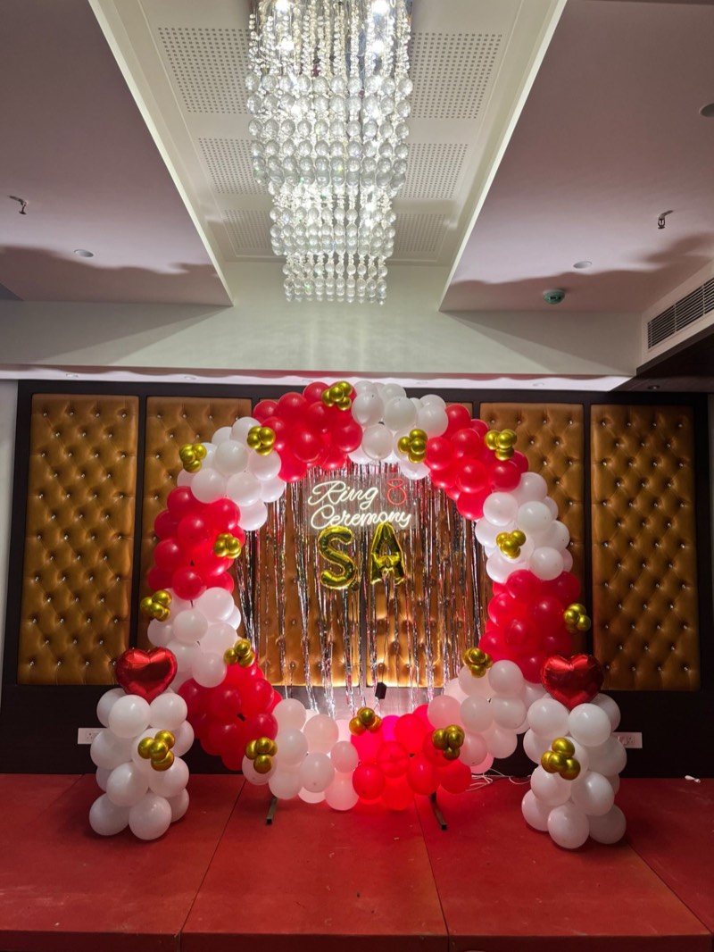 Red, white and gold balloon ring with a neon Ring Ceremony sign on a stage