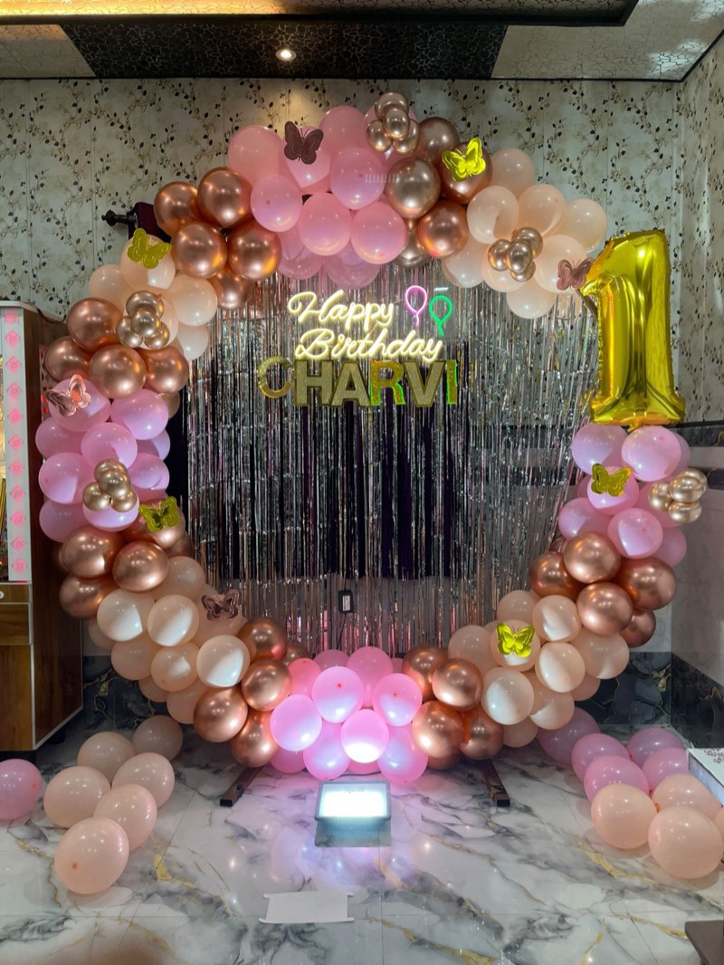 Rose-gold, blush and ivory balloon ring with a neon Happy Birthday sign and silver foil curtain