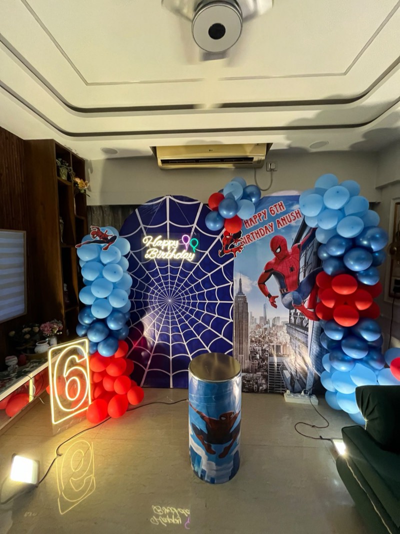 Spider-Man printed backdrop with sky-blue and red balloon columns, neon number six and a printed cake pedestal